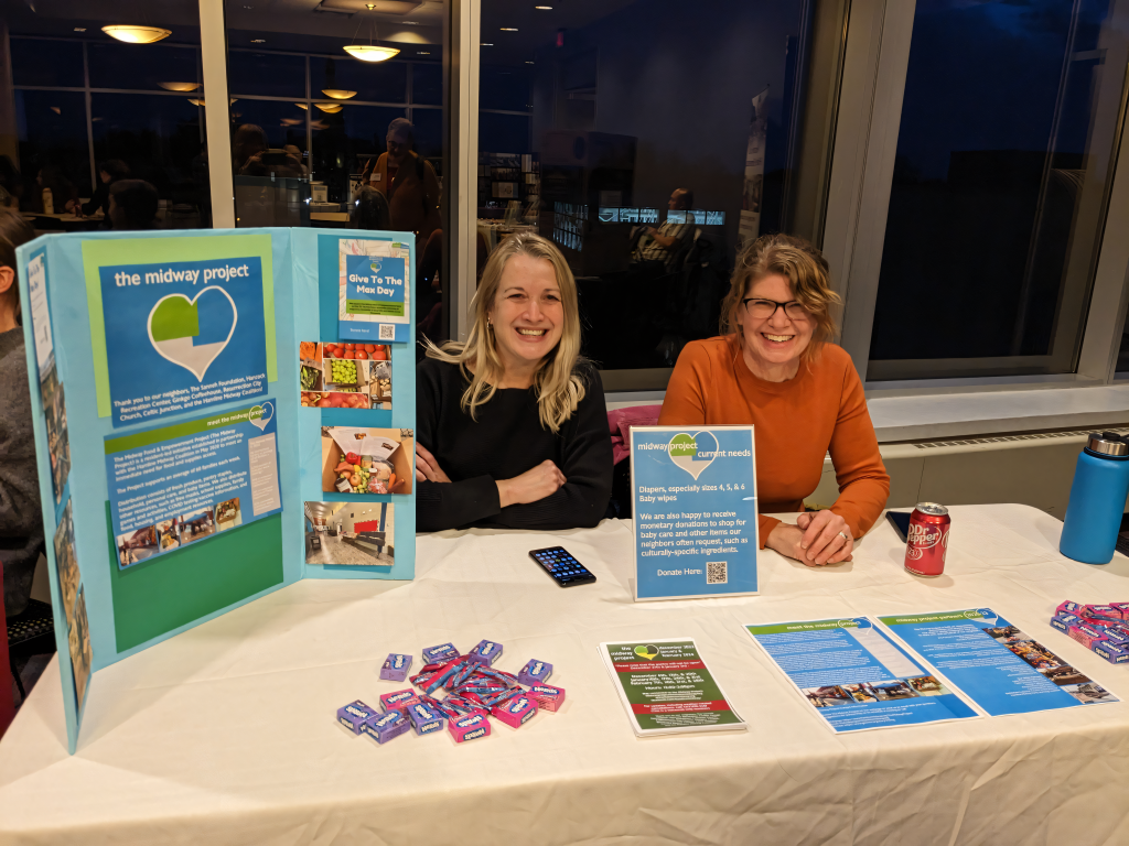 Two women at a folding table advertising their program