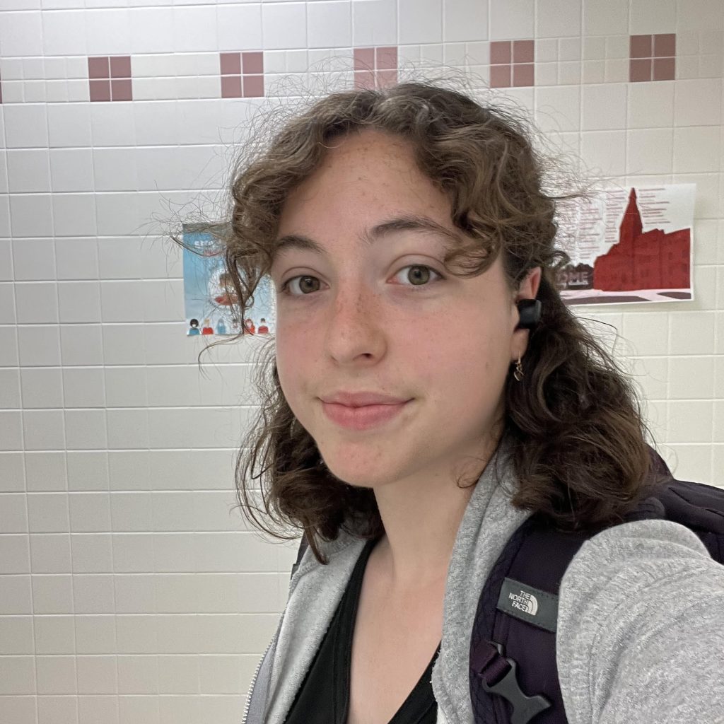 A photo of Cece Cmelik, a young woman with brown hair and in front of a tile background.