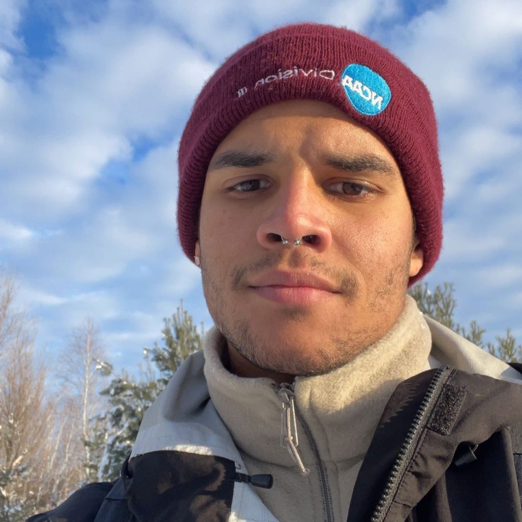 A photo of Lucas, a young man in a maroon hat and jacket.